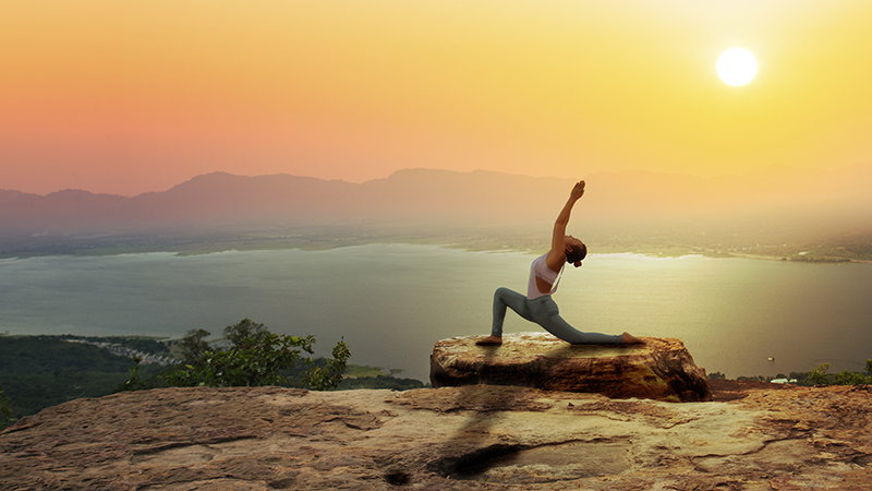 Woman on a cliff performing yoga.